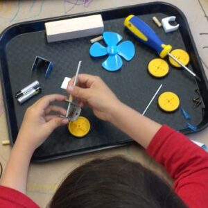 photograph of a tray of parts and a child's hands putting some together