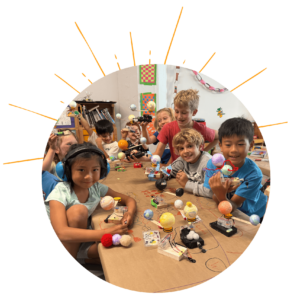 Photo: Table full of children holding robots they built