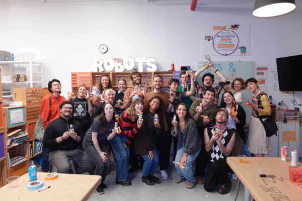 Photograph of a large group of adults happily holding up the robots they built.