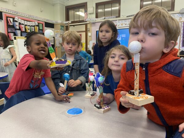 Photo of a bunch of children holding up their robots to camera