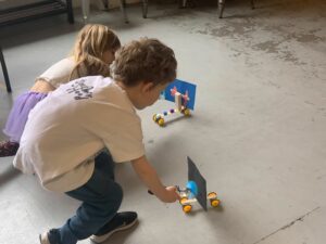 2 kids playing with a Windy Winder robot on the floor