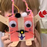 Photo of a child holding a robot they built in front of their face