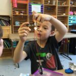 Photo of a child showing another child their lit-up LED circuit