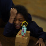 Photo of a child laughing with a robot in front of them