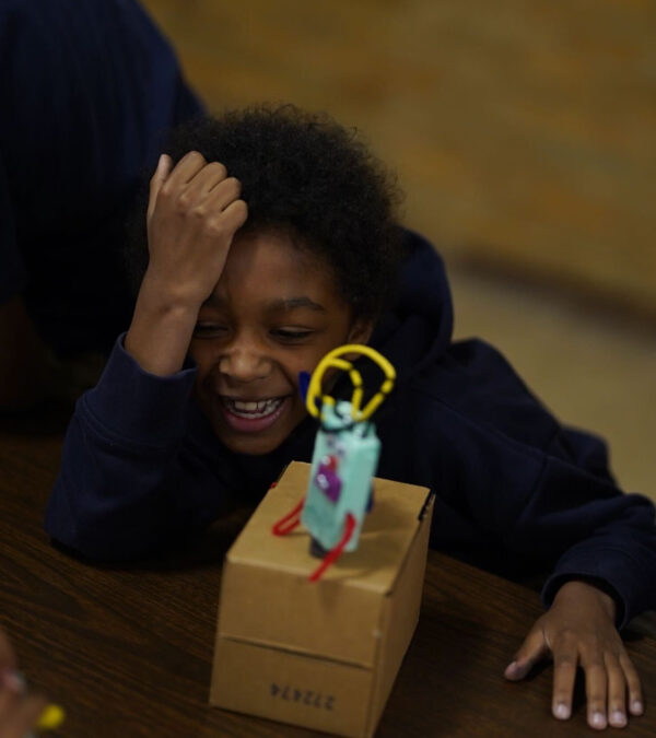 Photo of a child laughing with a robot in front of them