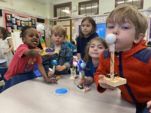 Photo of a bunch of children holding up their robots to camera