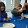 Photo of 3 students building their robots at blue table