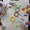 Overhead photo of kids decorating their robots with lots of markers and colorful tape in front of them