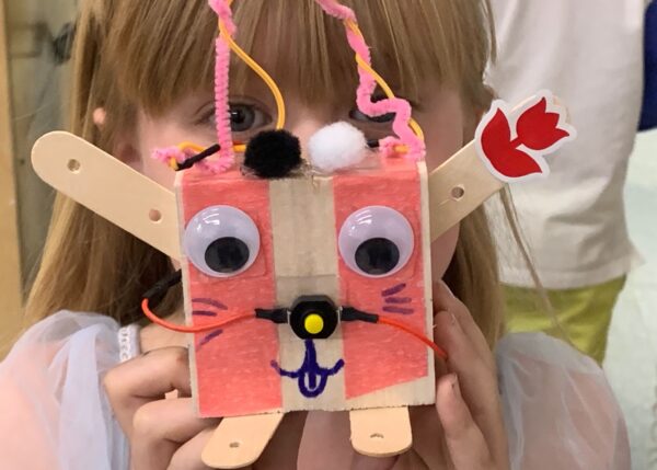 Photo of a child holding a robot they built in front of their face