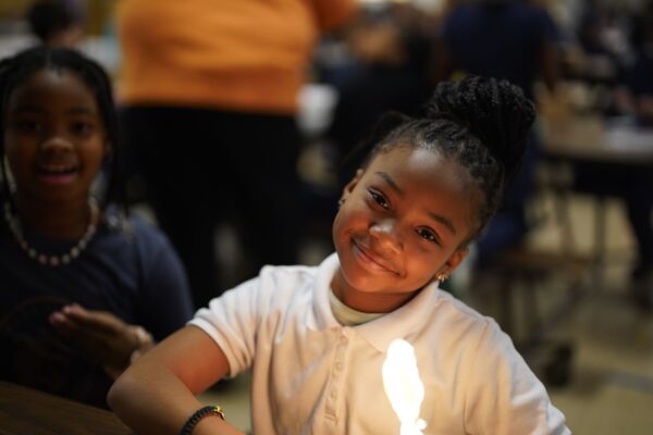 Photo of a child smiling at camera with a robot lit up in front of them