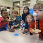 Photo of a bunch of children holding up their robots to camera