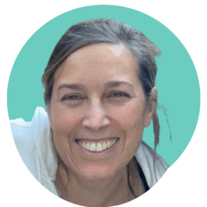 A photo head shot of owner, Kim Haden with a teal background