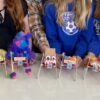 Photo of a bunch of robots lined up, held by the kids who built them