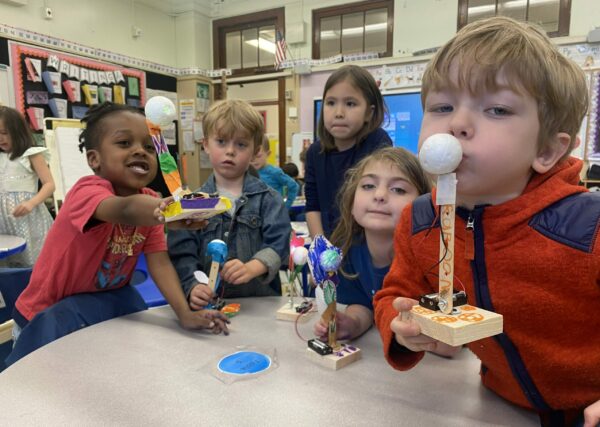 Photo of a bunch of children holding up their robots to camera