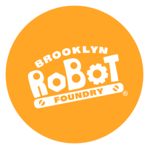 Orange circle outlined in white with white Brooklyn Robot Foundry logo in the center and registered "R" in a circle mark. "Brooklyn" is in all-caps, curved at the top. "Robot" is large in the middle, with the first o as a bolt and the second o as a gear. "Foundry" is at the bottom in an orange oval, with two screwheads on either end.