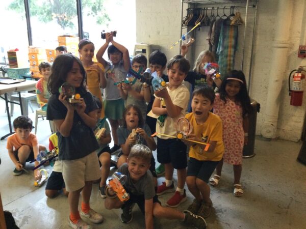 Group of kids excitedly holding up their finished robots.