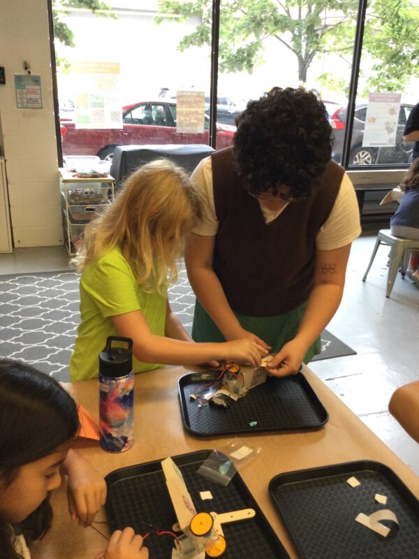 Photo of a teacher assisting a student as they build a robot