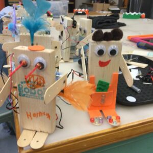 Photo of many robots on a tabletop with googly eyes and pom pom decorations