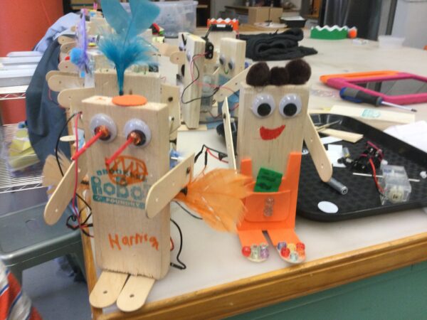 Photo of many robots on a tabletop with googly eyes and pom pom decorations