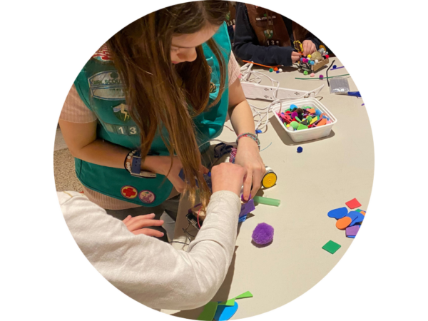 Circular photo of two students building a robot together.