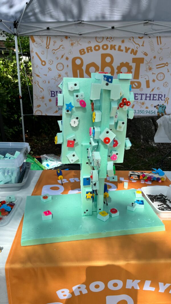 A table with a big tree made out of foam with lots of buttons and beads screwed into it.