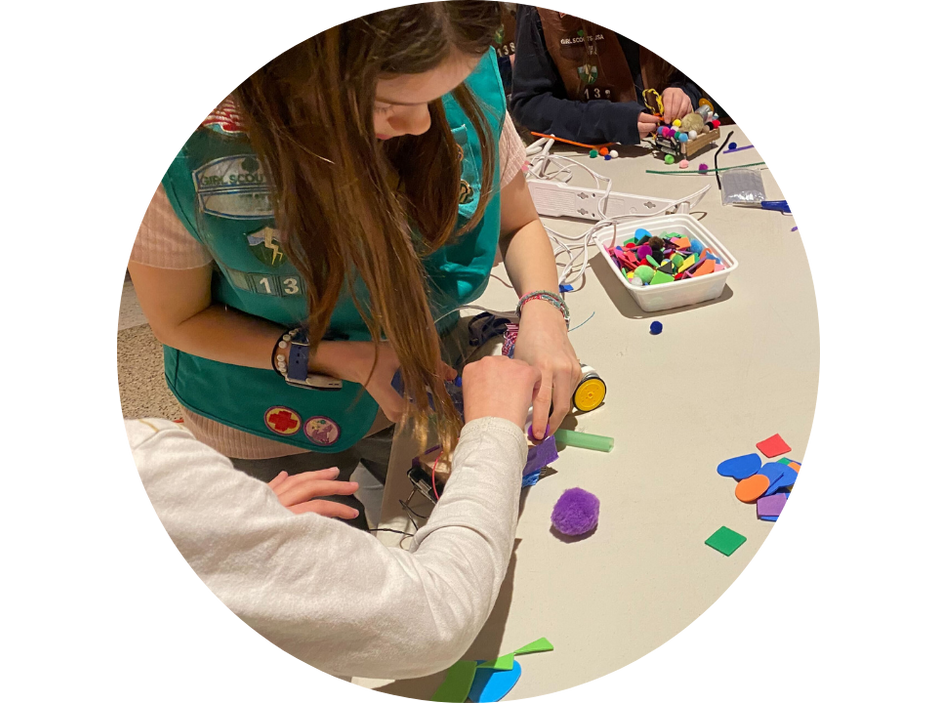 Photograph of two children working together on a robot. In a circular frame.